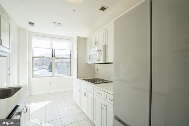 kitchen with light tile patterned flooring, sink, stainless steel dishwasher, black electric stovetop, and white cabinets