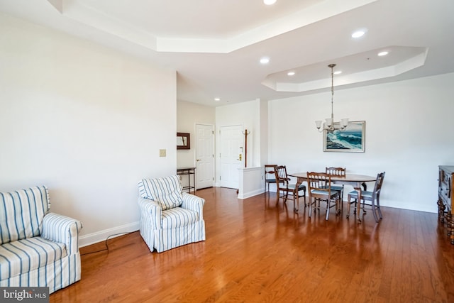 dining area featuring an inviting chandelier, wood-type flooring, and a tray ceiling