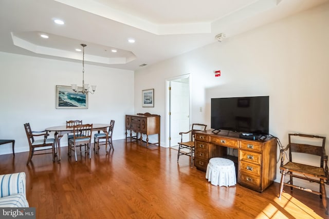 living room featuring hardwood / wood-style floors, a tray ceiling, and a notable chandelier