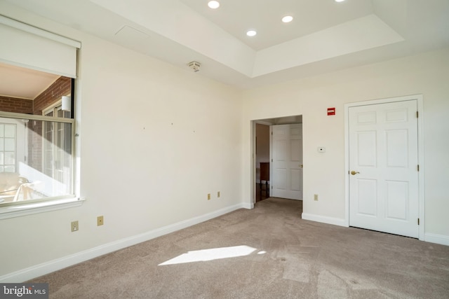 unfurnished bedroom with a tray ceiling and light carpet