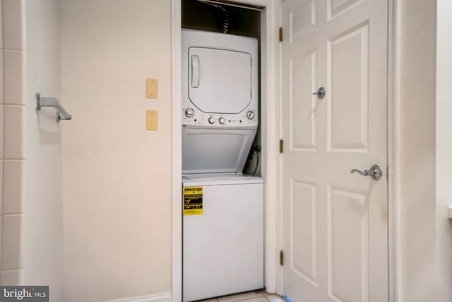 laundry area with stacked washer and dryer and light tile patterned floors