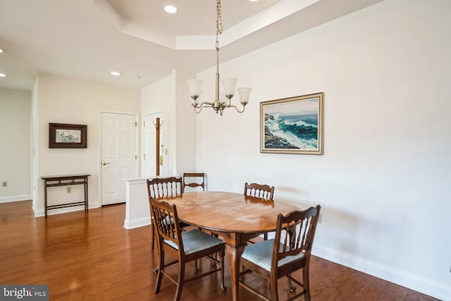 dining room featuring dark wood-type flooring, a tray ceiling, and a chandelier