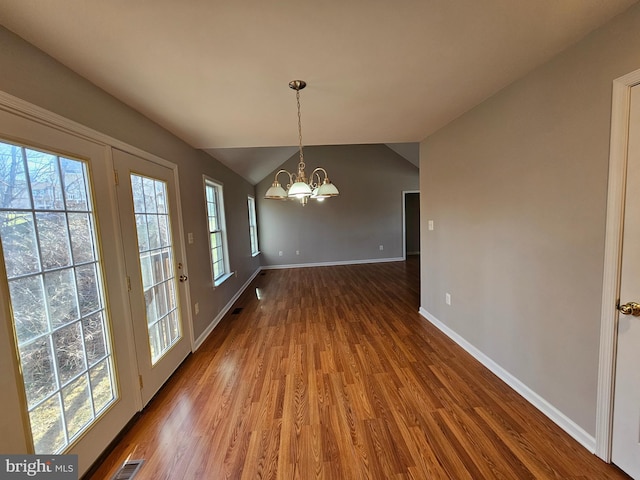 unfurnished dining area featuring hardwood / wood-style flooring, vaulted ceiling, and a notable chandelier