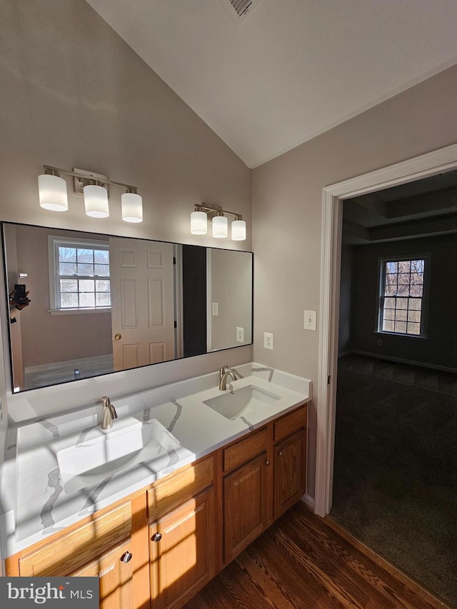 bathroom featuring hardwood / wood-style flooring, plenty of natural light, vaulted ceiling, and vanity