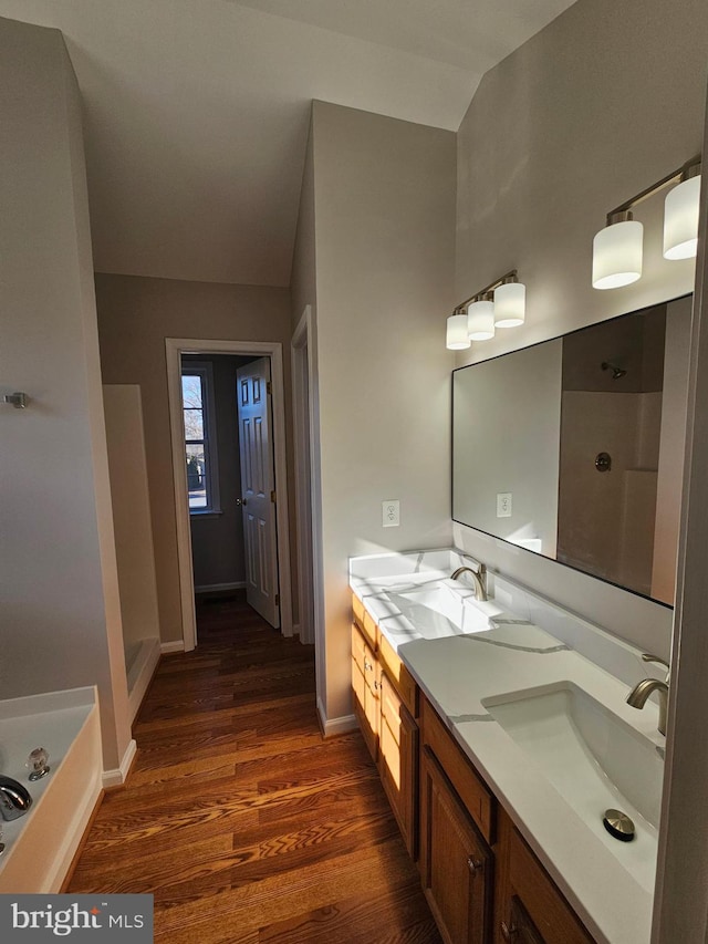 bathroom featuring vanity, wood-type flooring, and a tub