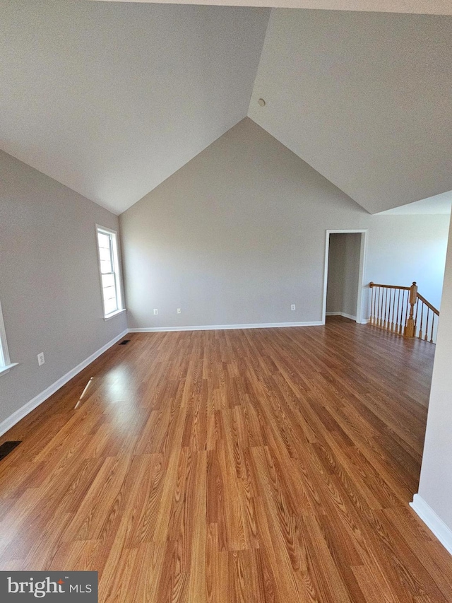 spare room with lofted ceiling and light wood-type flooring