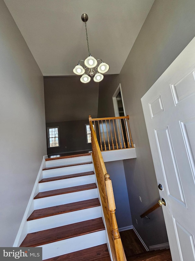 stairs with a notable chandelier and hardwood / wood-style flooring