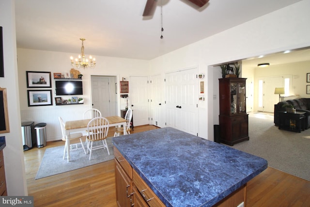 dining room with ceiling fan with notable chandelier and light hardwood / wood-style floors