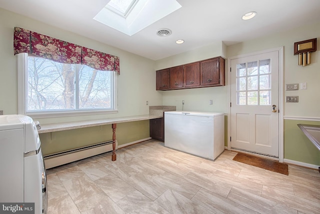 clothes washing area with cabinets, a skylight, washing machine and dryer, and a baseboard heating unit