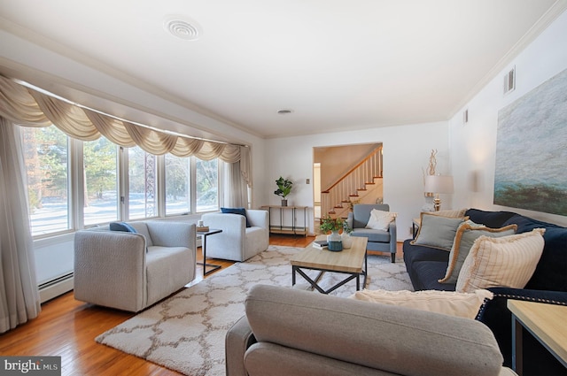 living room with a baseboard heating unit, crown molding, and light hardwood / wood-style floors