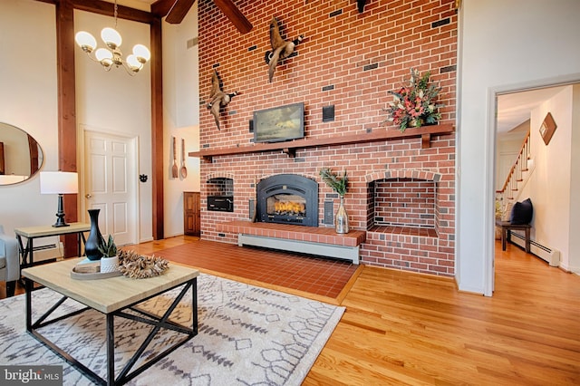 living room with a high ceiling, a fireplace, wood-type flooring, and baseboard heating