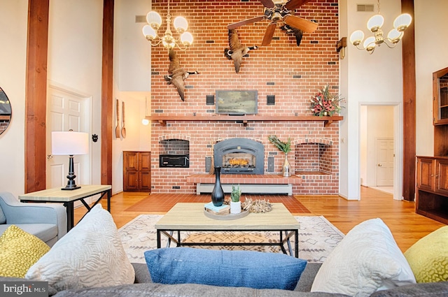 living room with light hardwood / wood-style flooring, a baseboard radiator, and a high ceiling