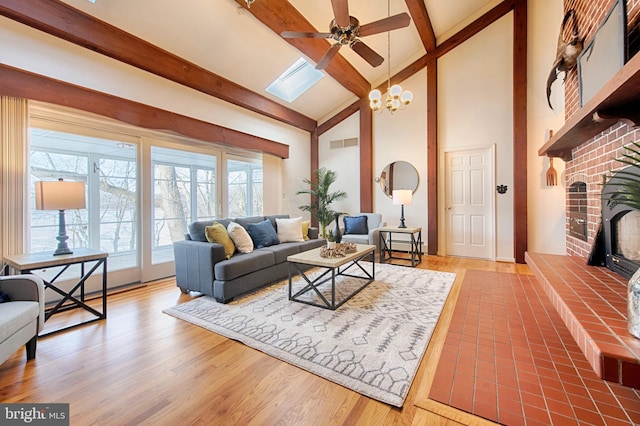 living room featuring beam ceiling, wood-type flooring, a fireplace, and a skylight