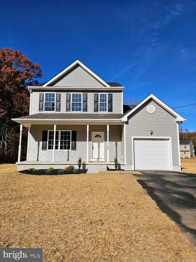 view of property featuring a garage, covered porch, and a front lawn