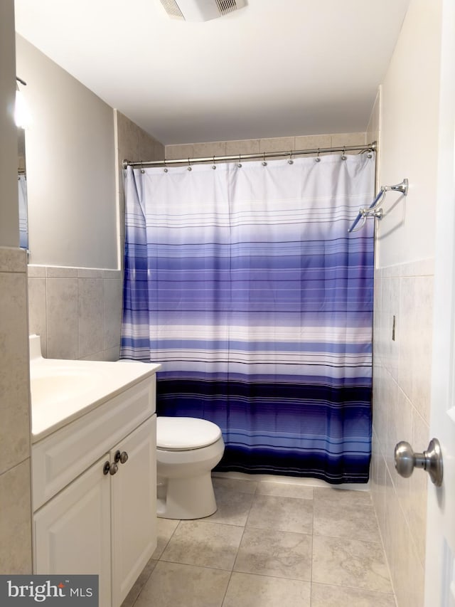 bathroom featuring tile patterned floors, vanity, toilet, and tile walls