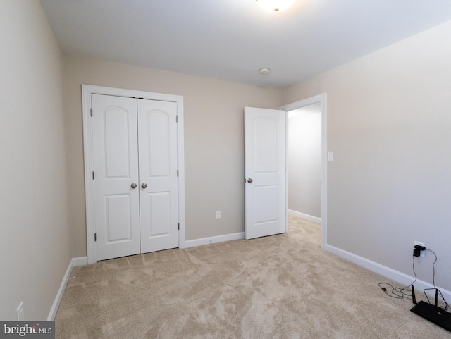 unfurnished bedroom with light colored carpet and a closet