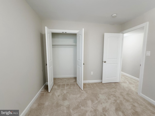 unfurnished bedroom featuring light carpet and a closet