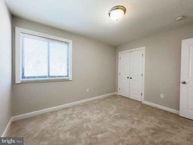 unfurnished bedroom with light colored carpet and a closet