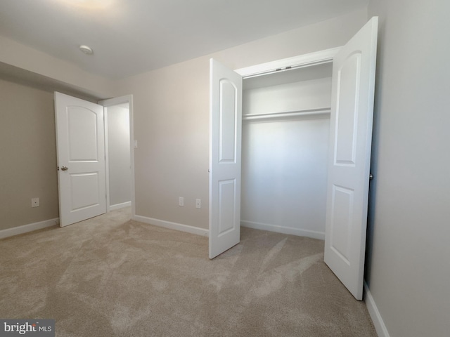 unfurnished bedroom with light colored carpet and a closet