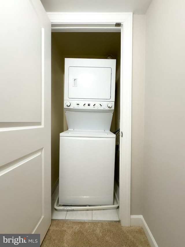 laundry area featuring light colored carpet and stacked washer and clothes dryer