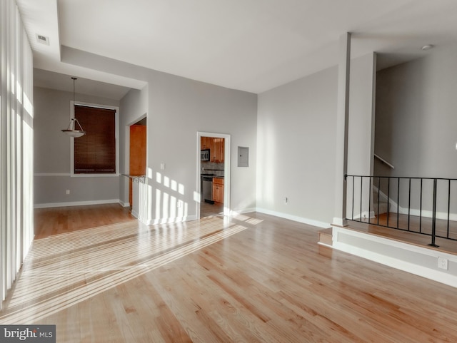 unfurnished living room with electric panel and light hardwood / wood-style flooring