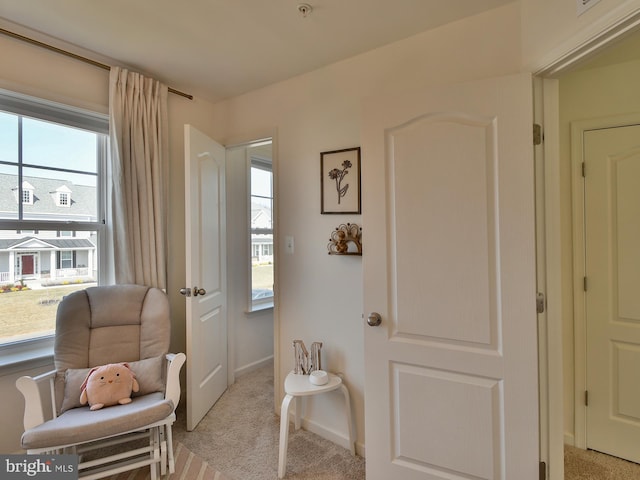 living area featuring baseboards and light colored carpet