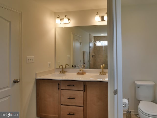 bathroom with double vanity, toilet, a stall shower, and a sink