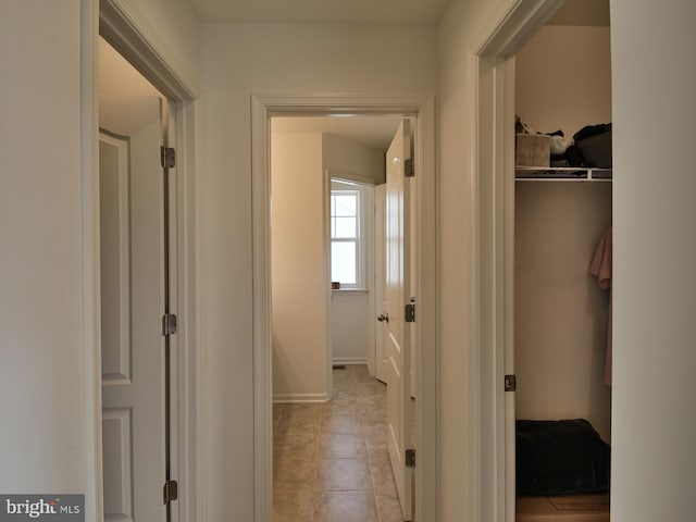 hallway featuring light tile patterned flooring and baseboards