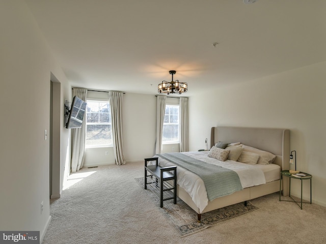 carpeted bedroom featuring baseboards and a notable chandelier