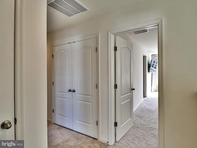 hallway with visible vents and light colored carpet