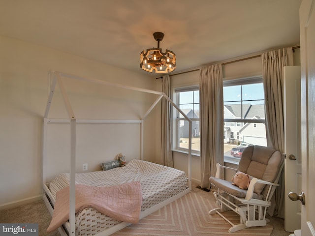 carpeted bedroom featuring a chandelier and baseboards