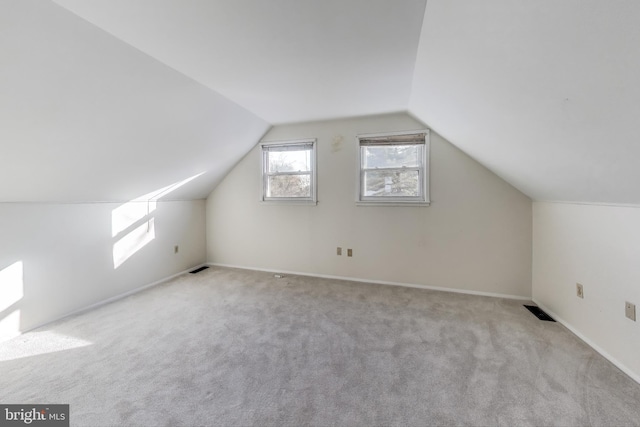 bonus room with vaulted ceiling and light carpet