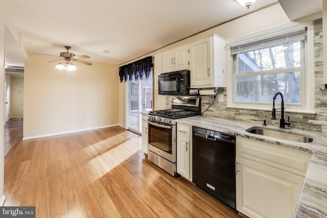 kitchen featuring sink, light stone counters, black appliances, white cabinets, and backsplash