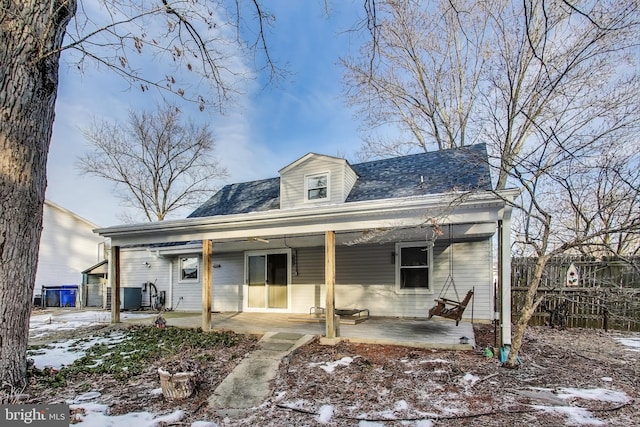 snow covered back of property with a patio