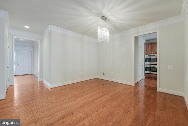 spare room featuring a notable chandelier, crown molding, and light hardwood / wood-style flooring