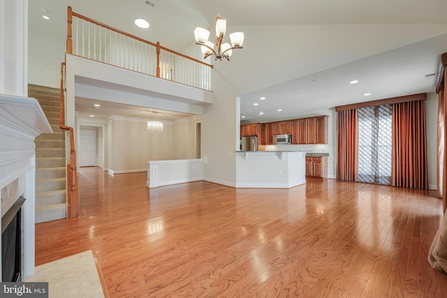 unfurnished living room featuring a high ceiling, light hardwood / wood-style flooring, and a notable chandelier