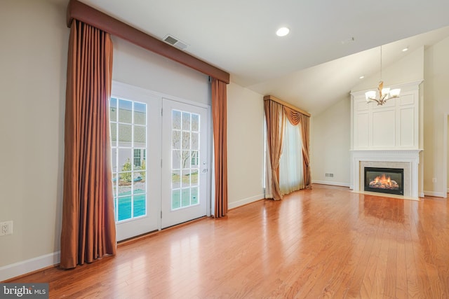 unfurnished living room with light hardwood / wood-style floors, vaulted ceiling, and a notable chandelier