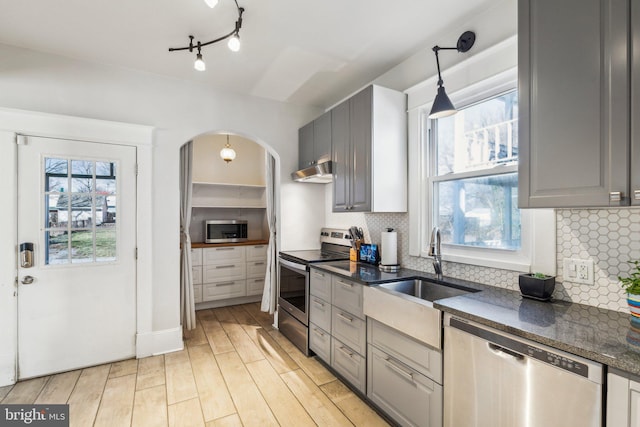 kitchen with hanging light fixtures, gray cabinets, light hardwood / wood-style floors, and appliances with stainless steel finishes