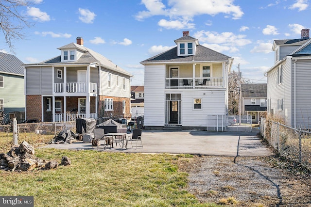 rear view of house featuring a balcony, a patio, and a lawn