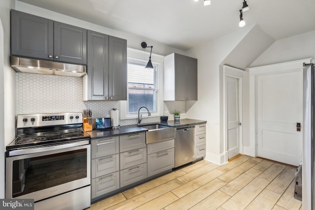 kitchen featuring sink, gray cabinetry, decorative backsplash, stainless steel appliances, and light wood-type flooring