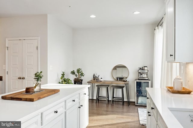 kitchen featuring white cabinetry, light hardwood / wood-style floors, and beverage cooler