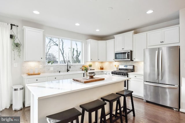 kitchen with a kitchen bar, sink, a kitchen island, stainless steel appliances, and white cabinets