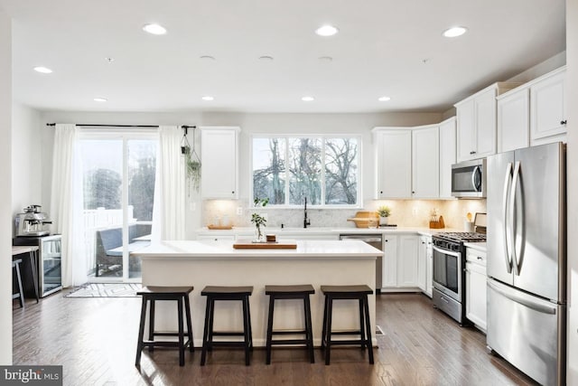 kitchen featuring a kitchen breakfast bar, a center island, white cabinets, and appliances with stainless steel finishes