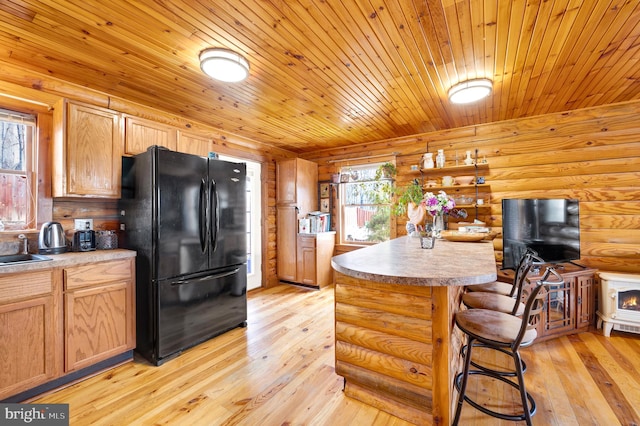 kitchen with light wood-style flooring, freestanding refrigerator, a healthy amount of sunlight, and log walls