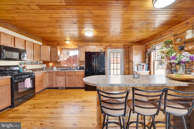 kitchen with wooden ceiling, a sink, light wood-style floors, black appliances, and a kitchen bar