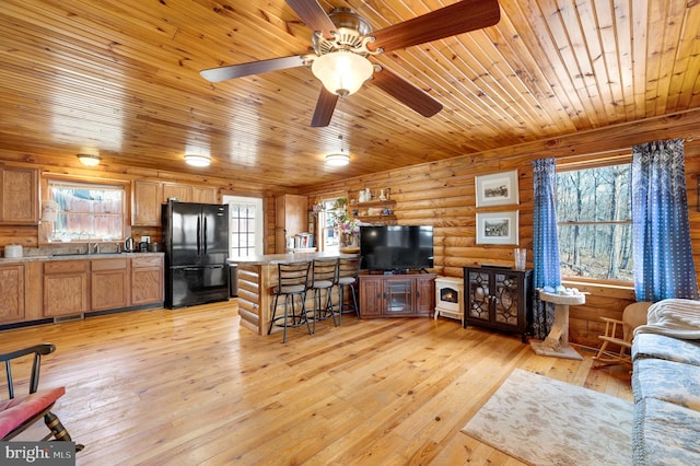 living area featuring light wood-type flooring, wooden ceiling, visible vents, and log walls