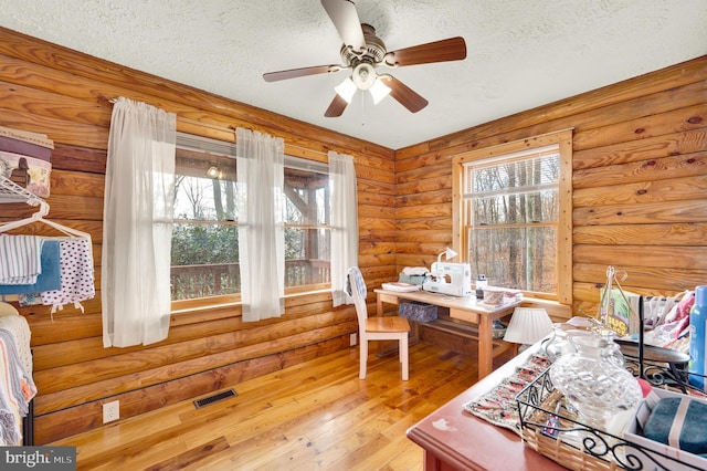 office space with wood-type flooring, visible vents, ceiling fan, and a textured ceiling