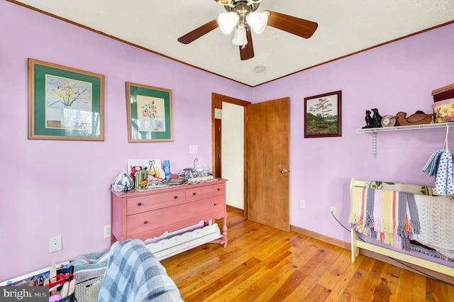 bedroom with baseboards, a ceiling fan, light wood-style flooring, and crown molding