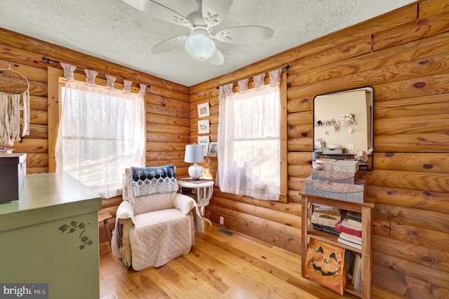 sitting room featuring a textured ceiling, visible vents, hardwood / wood-style flooring, and a ceiling fan