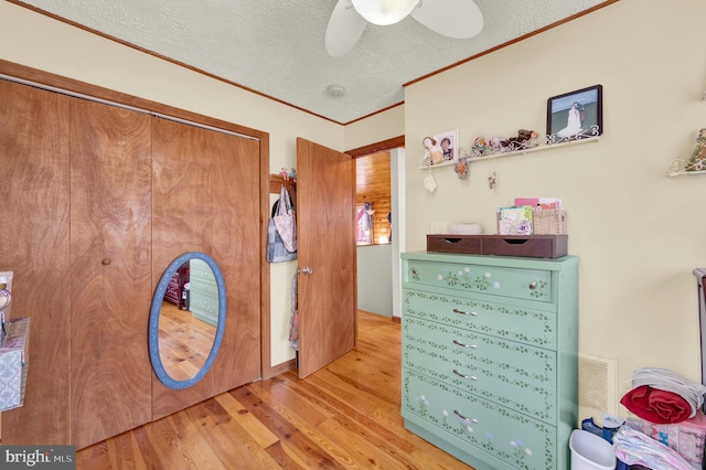 bedroom with a textured ceiling, wood finished floors, a ceiling fan, a closet, and crown molding